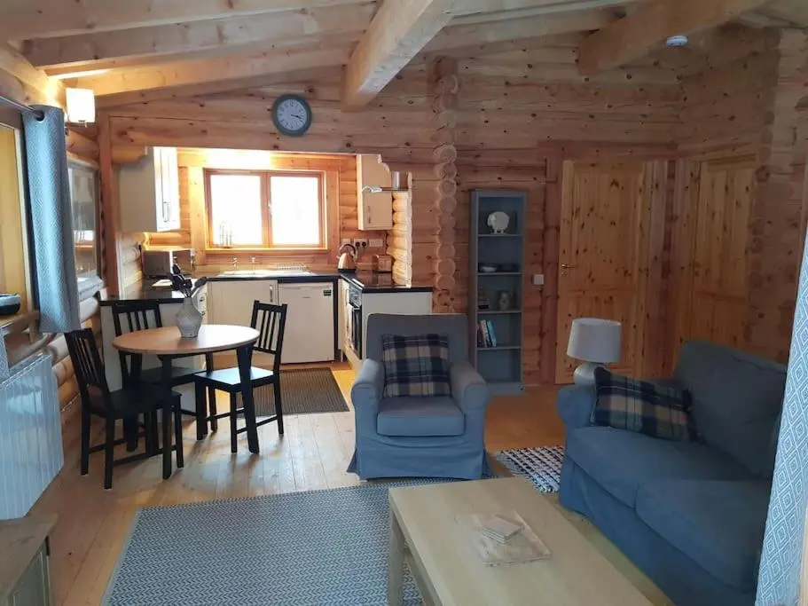 a living room with a blue couch and a table at Orchid lodge in Bridge of Tilt