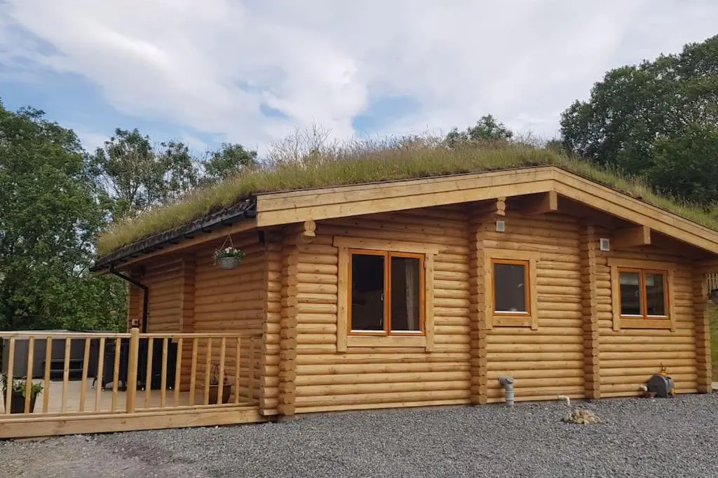 a log cabin with a grass roof at Orchid lodge in Bridge of Tilt