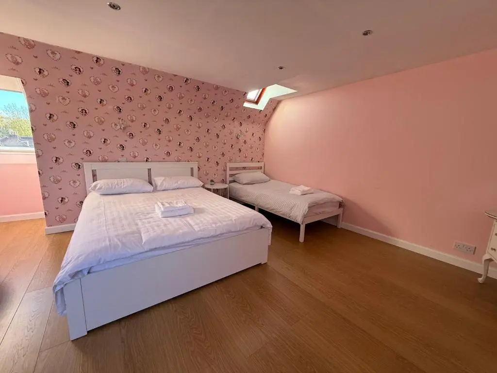 a bedroom with two beds and a pink wall at Sunshine three bedrooms Apartment in Insch