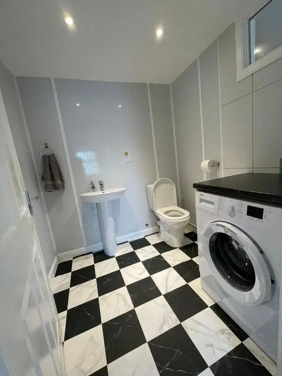 a bathroom with a sink and a washing machine at Sunshine three bedrooms Apartment in Insch