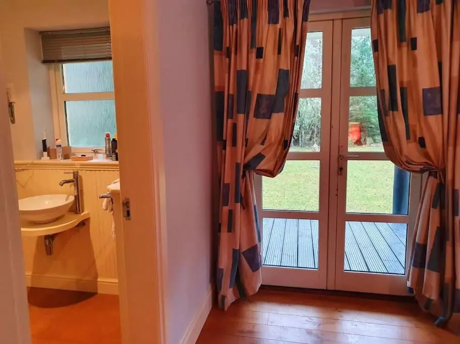 a bathroom with a sink and a door with a window at Heath House Loch Ness in Errogie