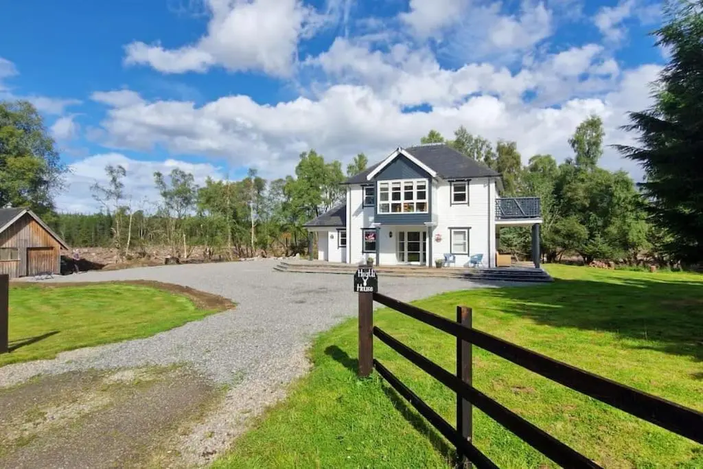 a white house with a fence next to a driveway at Heath House Loch Ness in Errogie