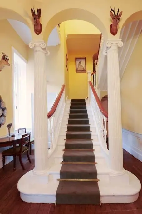 a staircase with white columns in a living room at Idyllic 12 bedroom Country Home in Forres