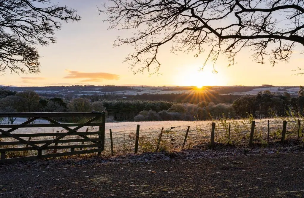 a gate in a field with the sunset in the background at Cherry Tree Lodge in Inverness