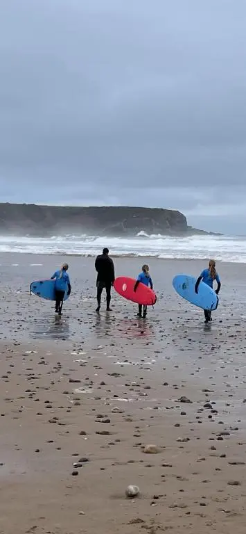 a group of people walking on the beach with their surfboards at Cobblehouse Country Cabins no TRADE WORKERS in Inverkeithny