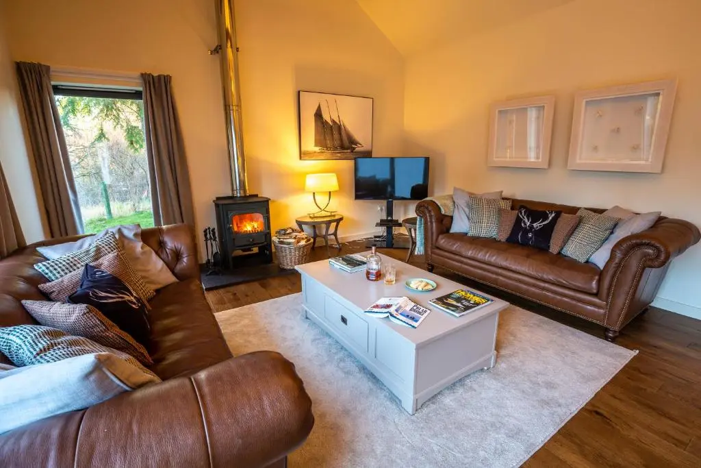 a living room with leather couches and a coffee table at Riverside Lodge - Seasgair Lodges in Nethy Bridge