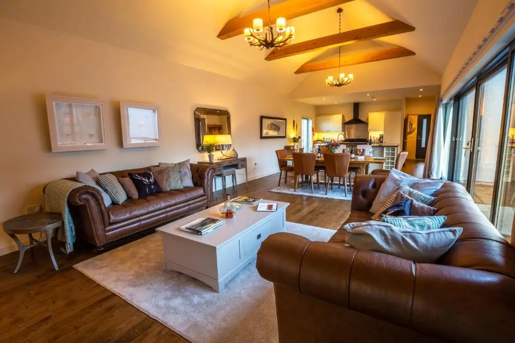 a living room with a couch and a table at Riverside Lodge - Seasgair Lodges in Nethy Bridge