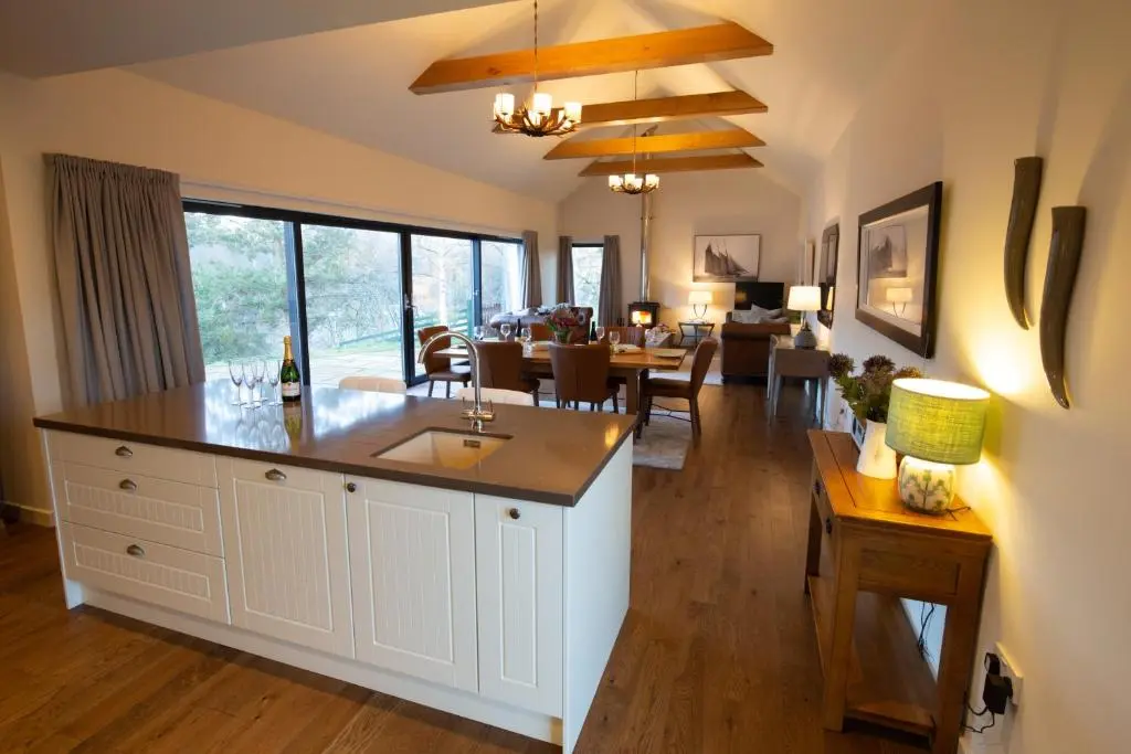 a kitchen and living room with a dining room at Riverside Lodge - Seasgair Lodges in Nethy Bridge