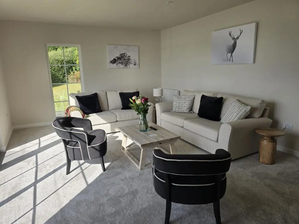 a living room with a couch and chairs and a table at Linden Cottage in Fortrose