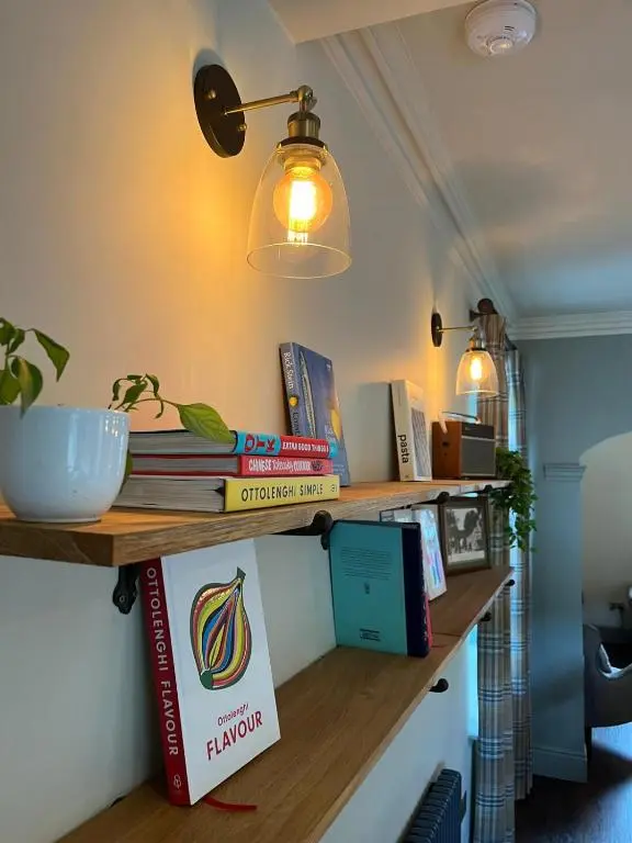 a shelf with books and a light on a wall at Lewis Lodge - Stunning & Exclusive Luxury Home in the Heart of Ballater, Royal Deeside in Ballater