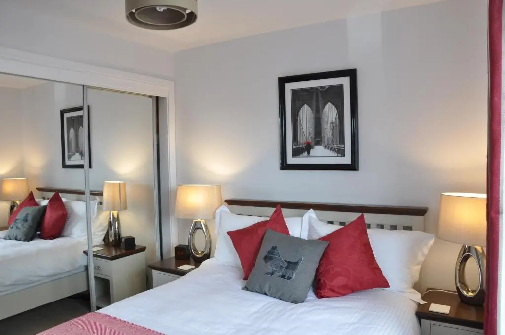 a bedroom with two beds with red and grey pillows at Westgate Apartments Birchlee in Inverurie