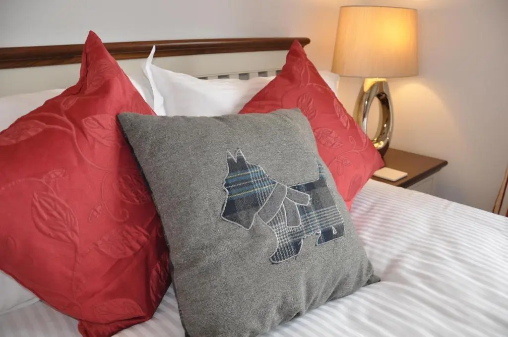 a bed with red and blue pillows on it at Westgate Apartments Birchlee in Inverurie