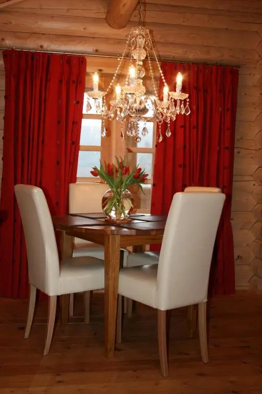 a dining room table with white chairs and a chandelier at BCC Loch Ness Log Cabins in Bearnock