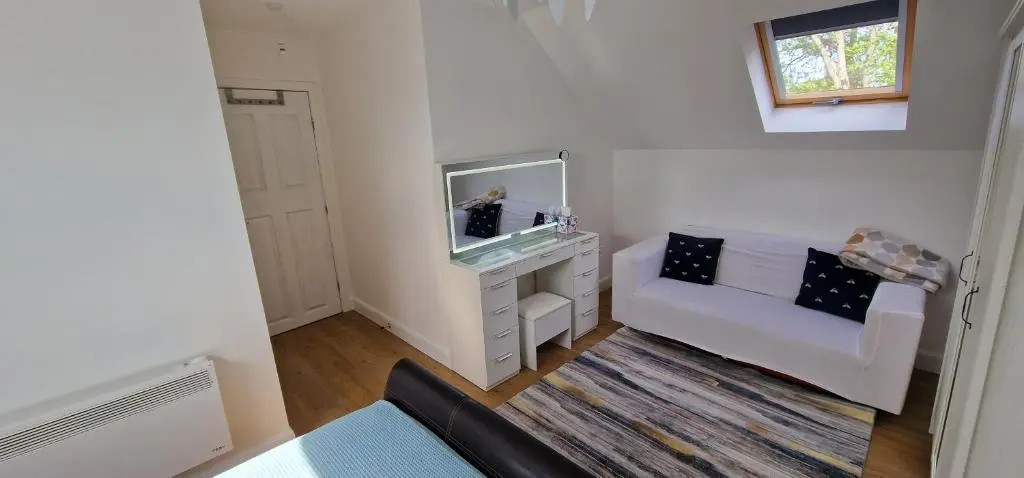 a living room with a white couch and a mirror at The Flat at Clocktower Buildings in Kinloss