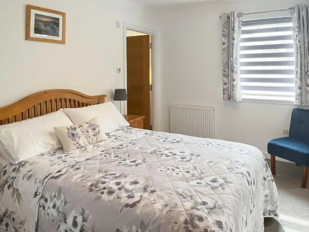 a bedroom with a bed and a blue chair at No 8 Cottage in Aviemore