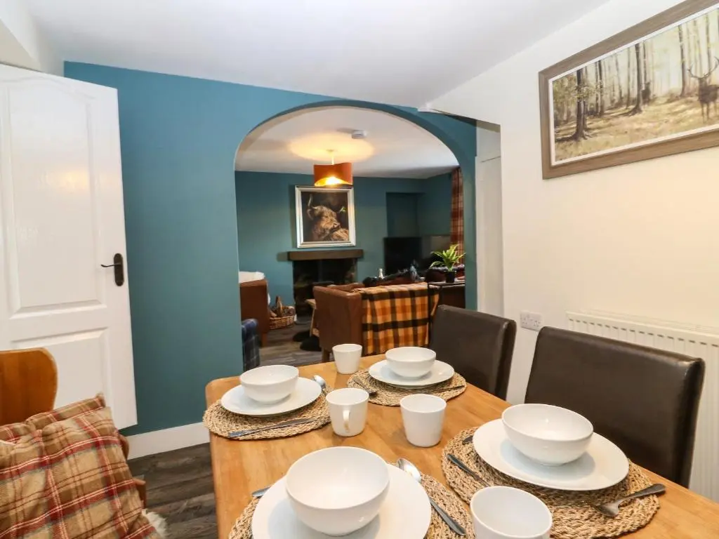 a dining room with a wooden table and chairs at West Pier Cottage in Macduff