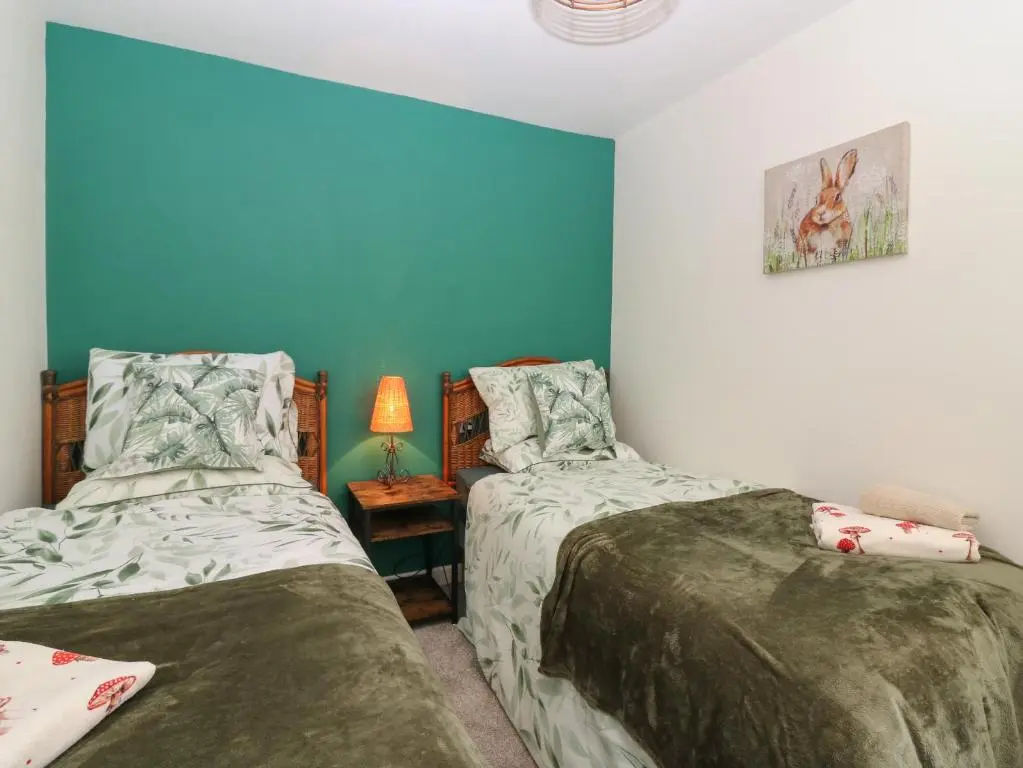 two beds in a room with blue walls at West Pier Cottage in Macduff