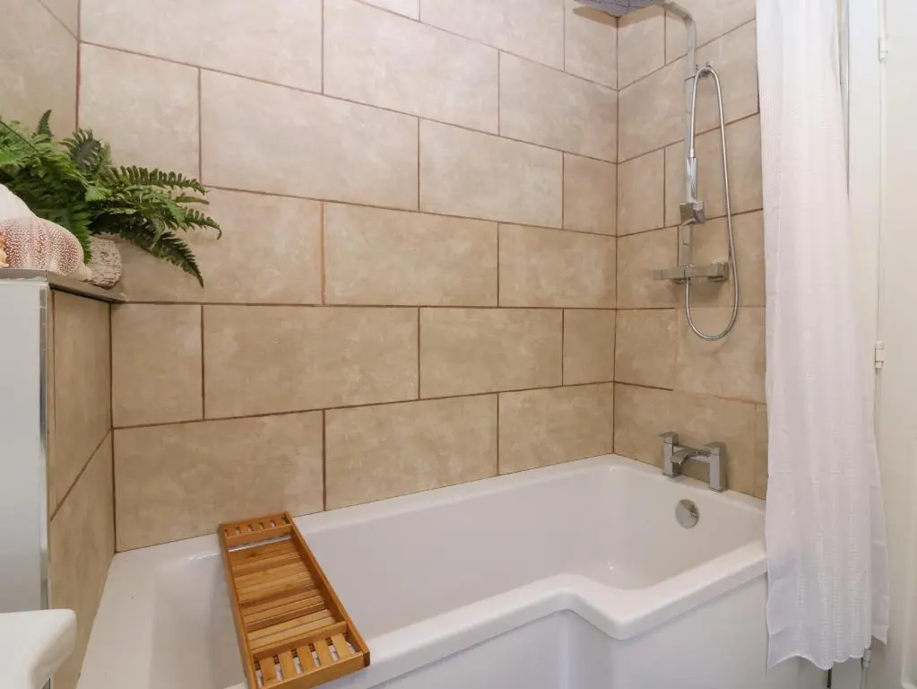 a bathroom with a white tub and a shower at West Pier Cottage in Macduff
