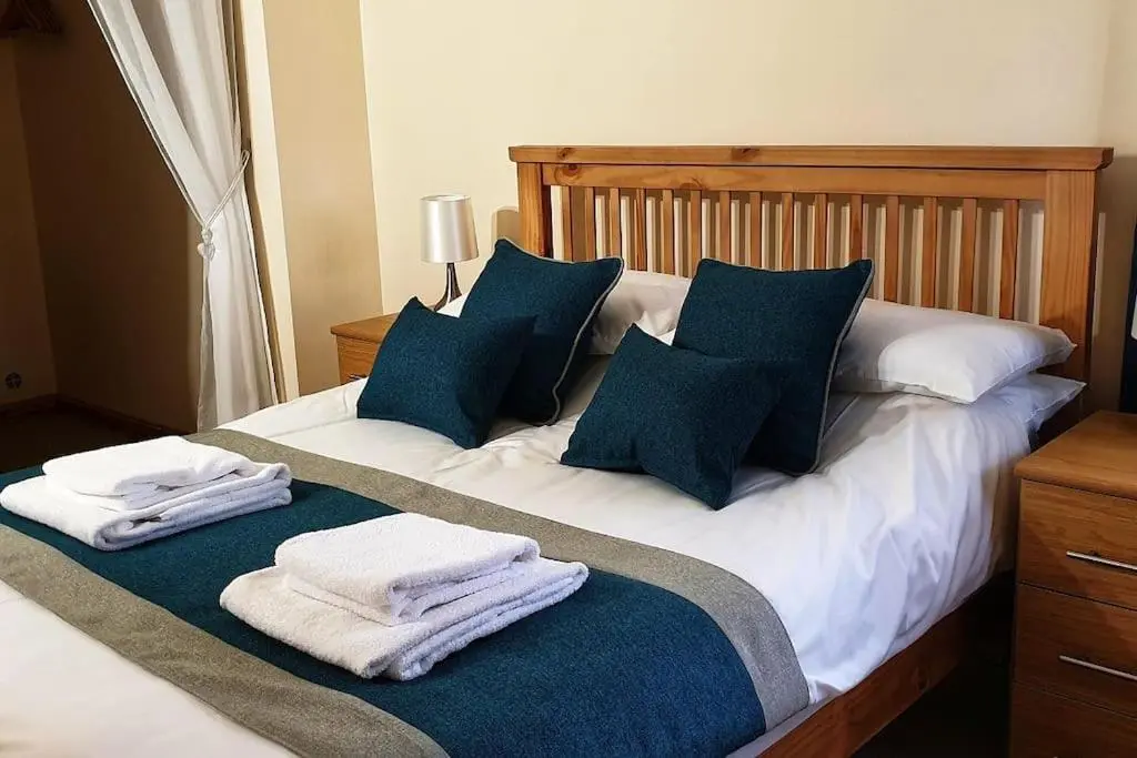 a bed with blue and white pillows and towels on it at Findhorn Bay - Sandpiper Eco chalet in Findhorn