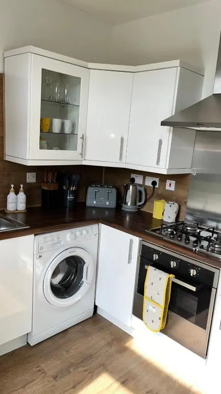 a white kitchen with a washing machine and a stove at 23 Innes Street Apartment in Inverness