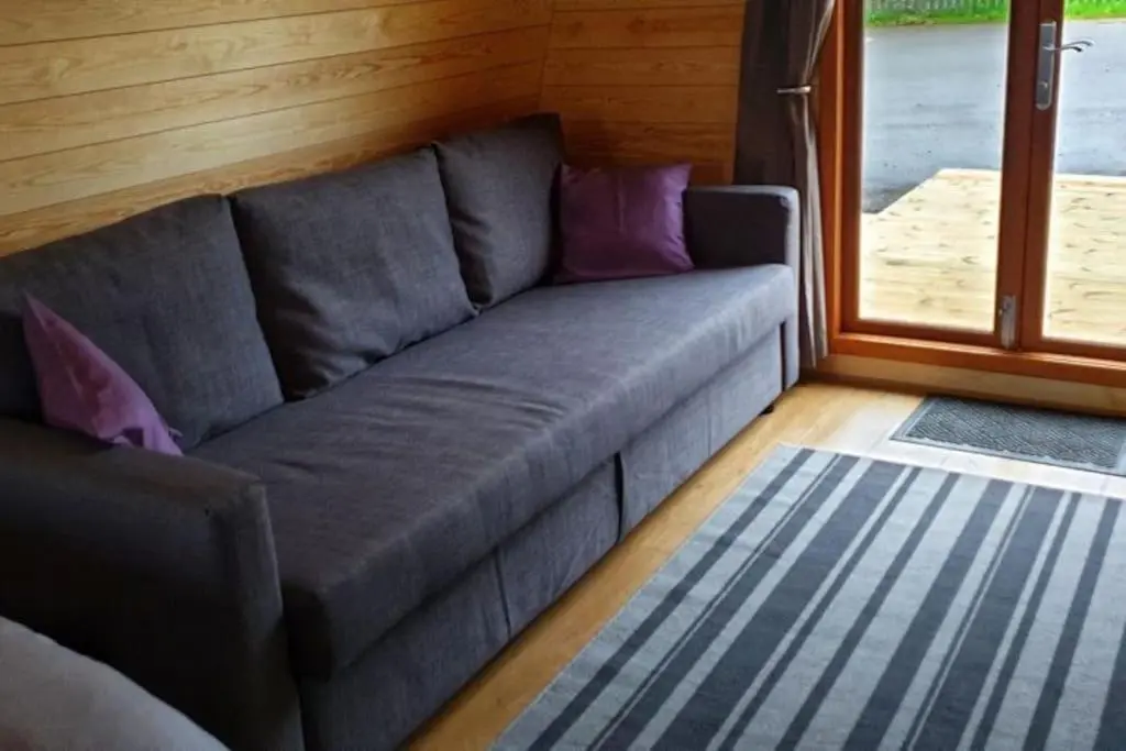 a gray couch in a room with a window at Findhorn Ecovillage Escape Eco Pod Pet free in Findhorn