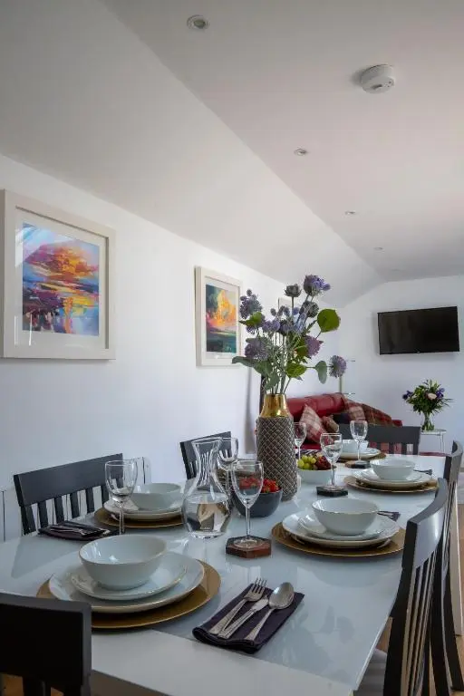 a dining room table with plates and wine glasses at Cairnie Cottage in Ballater