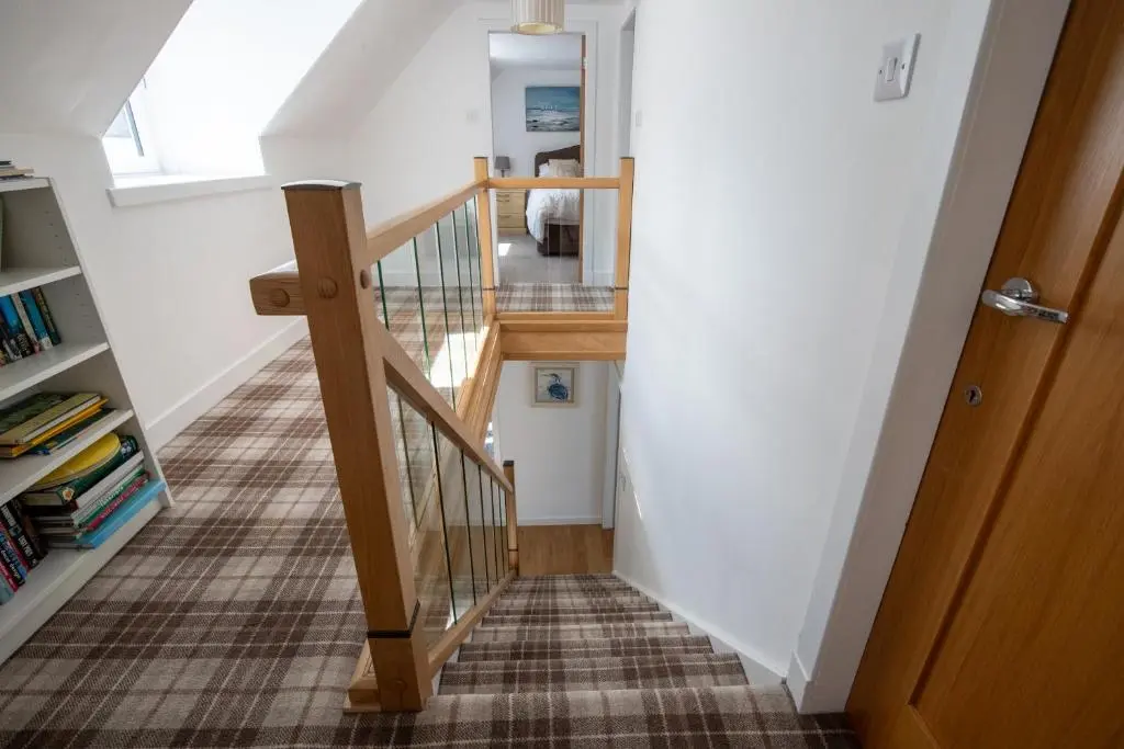 a stairwell with a wooden railing and a wooden door at Cairnie Cottage in Ballater