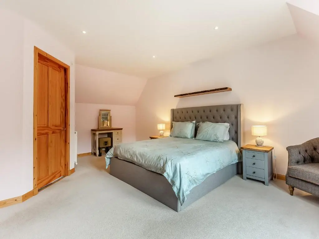 a bedroom with a large bed and a chair at Bridge House in Evanton