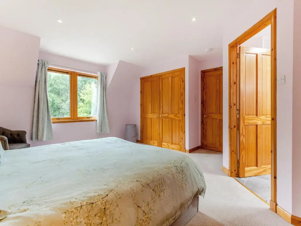 a bedroom with a large bed and wooden cabinets at Bridge House in Evanton