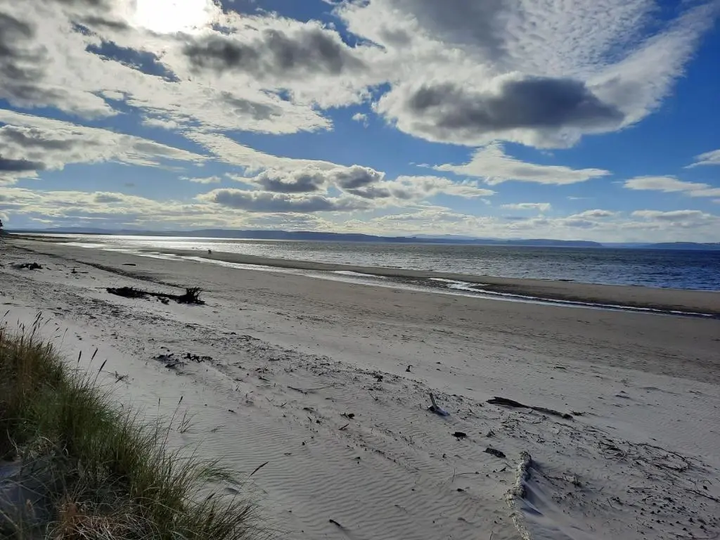 a beach with a cloudy sky and the ocean at The Nairn House in Nairn