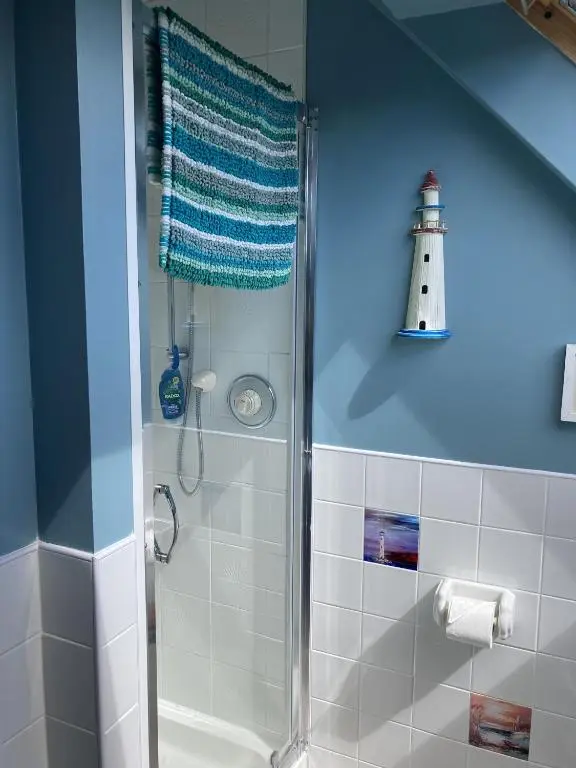 a bathroom with a shower with a lighthouse on the wall at The Nairn House in Nairn