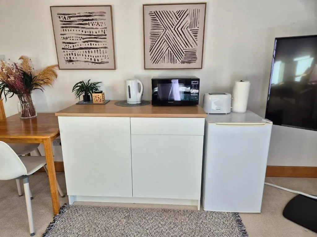 a kitchen with white cabinets and a table with a microwave at Twin Pines in Mulben