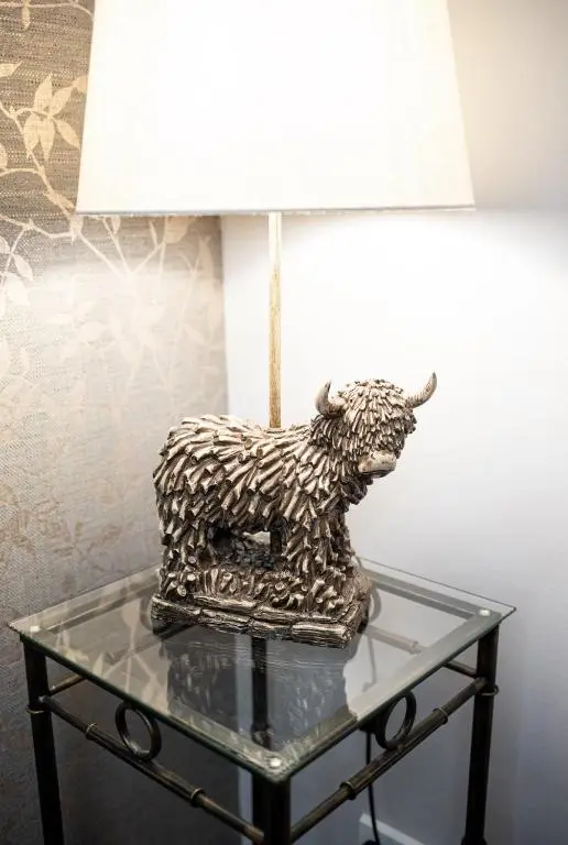 a lamp on a glass table with a statue of a sheep at Inverness Apartment - Uist in Inverness