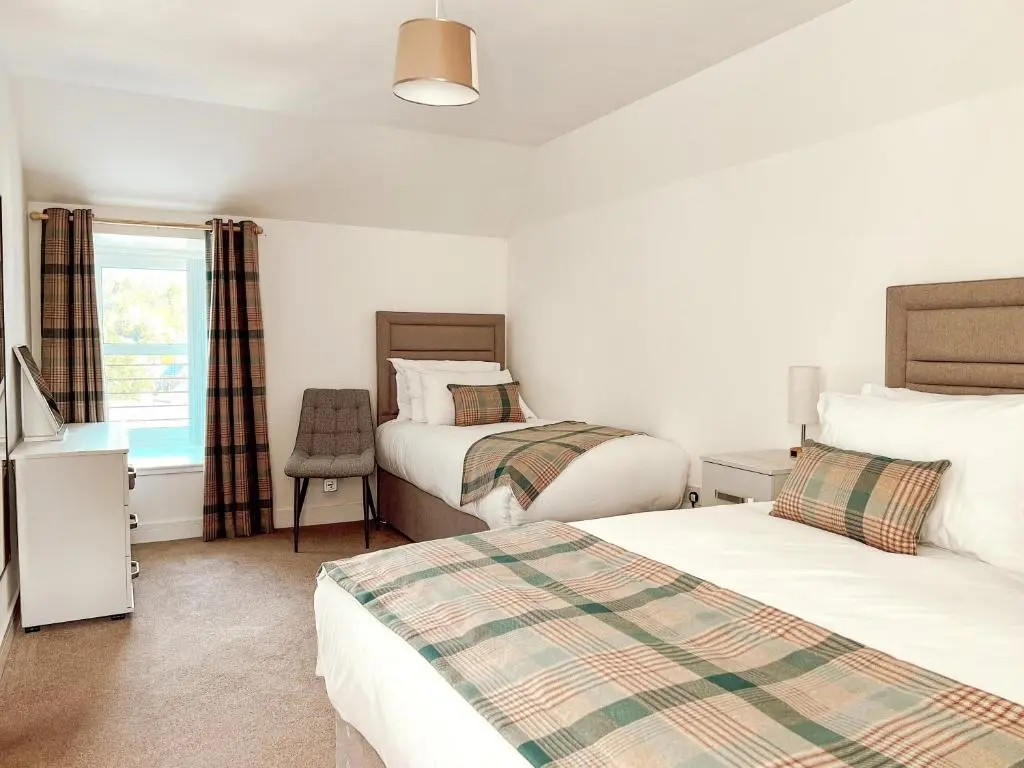 a bedroom with two beds and a window at Loch Ness Gatehouse Apartments in Fort Augustus