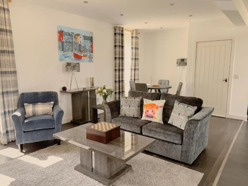 a living room with a couch and a table at Loch Ness Gatehouse Apartments in Fort Augustus