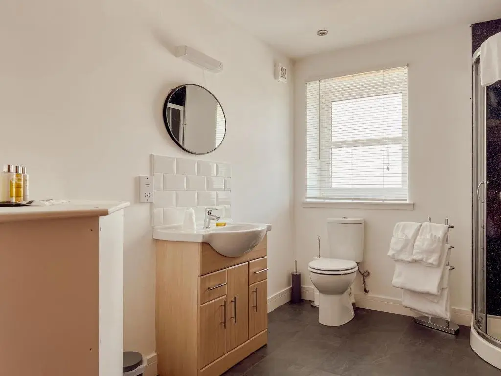 a bathroom with a sink and a toilet and a mirror at Loch Ness Gatehouse Apartments in Fort Augustus