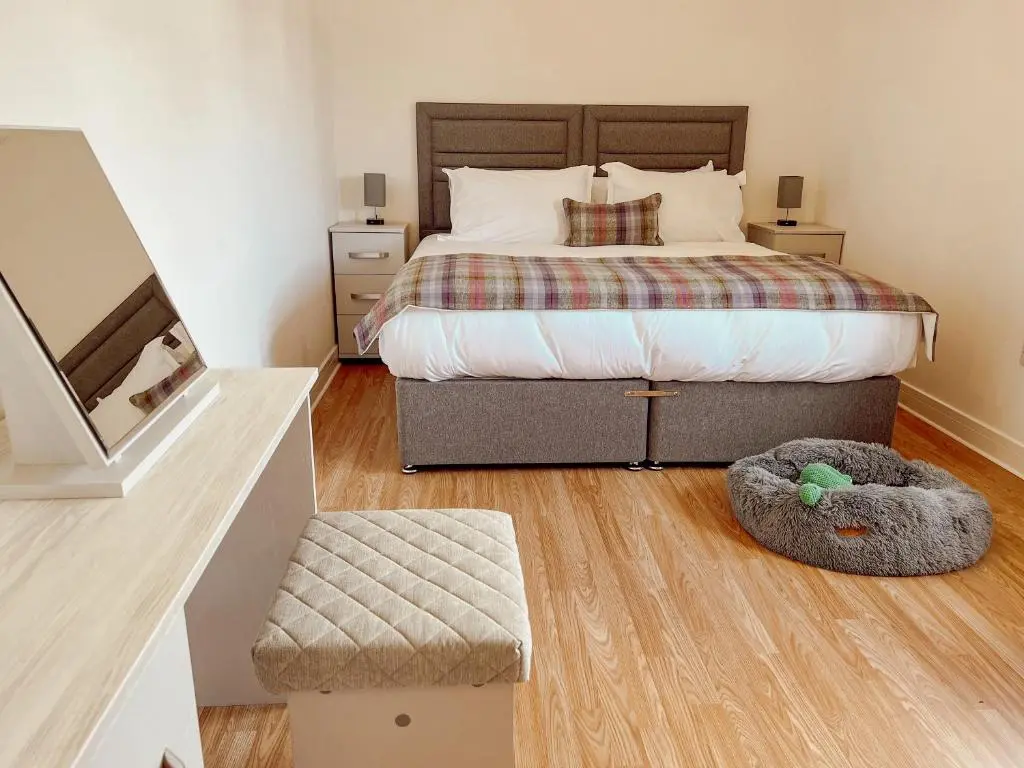 a bedroom with a large bed and a ottoman at Loch Ness Gatehouse Apartments in Fort Augustus