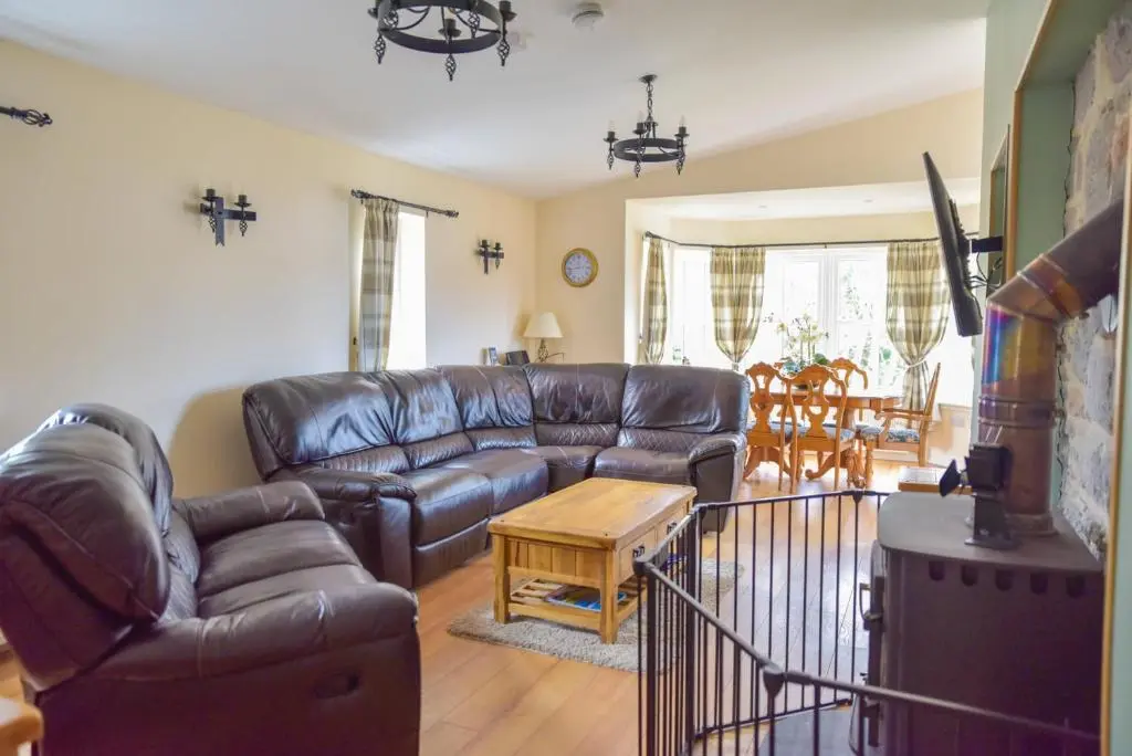 a living room with a leather couch and a table at Cosy Spacious Highland Cottage in Craggie