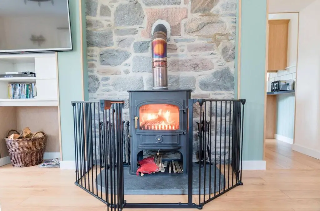 a stove in a living room with a stone wall at Cosy Spacious Highland Cottage in Craggie