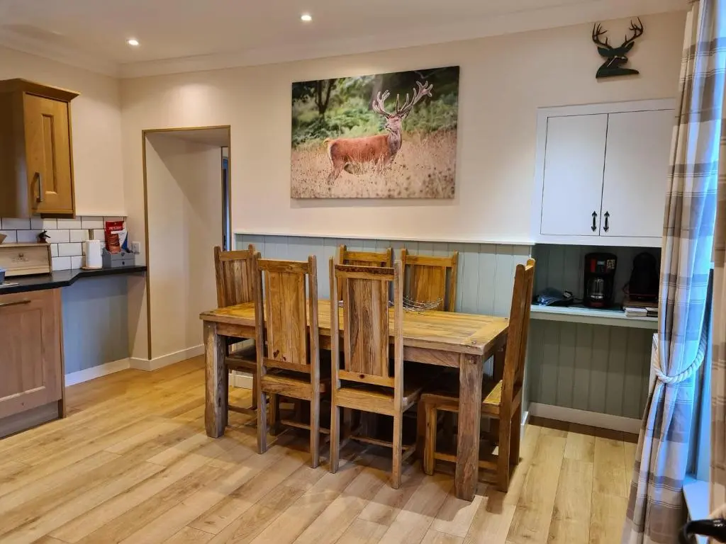 a kitchen with a wooden table and a deer on the wall at Cosy Spacious Highland Cottage in Craggie