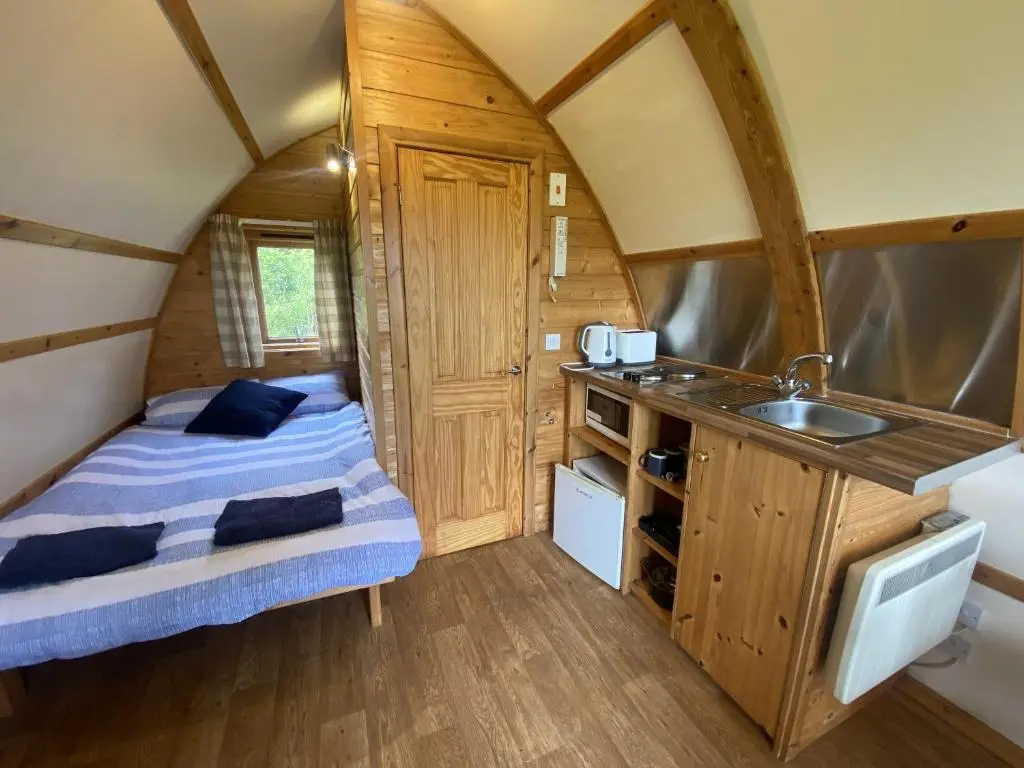 a small room with a bed and a sink in a tiny house at Greenley Croft Glamping by Wigwam in Crovie