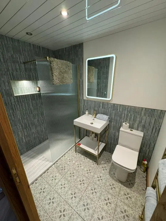 a bathroom with a shower and a toilet and a sink at Cosy Luxury apartment in Wick