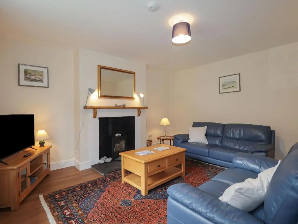 a living room with a blue couch and a fireplace at Gunroom Cottage in Strathpeffer