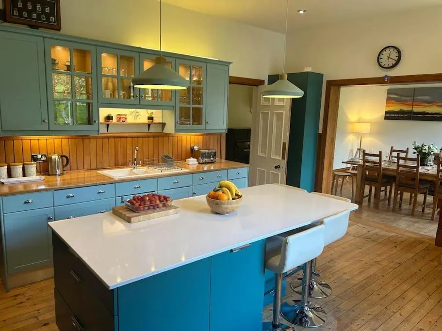 a kitchen with blue cabinets and a bowl of fruit on a counter at Victorian Home in Moray in Forres