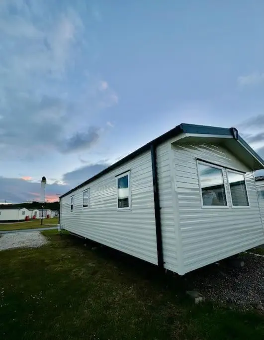 a small white trailer parked in a field at Sea La Vie Caravan at Silver Sands Holiday Park in Lossiemouth