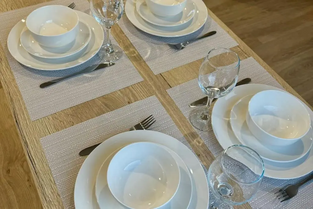 a table with white plates and wine glasses on it at Sea La Vie Caravan at Silver Sands Holiday Park in Lossiemouth