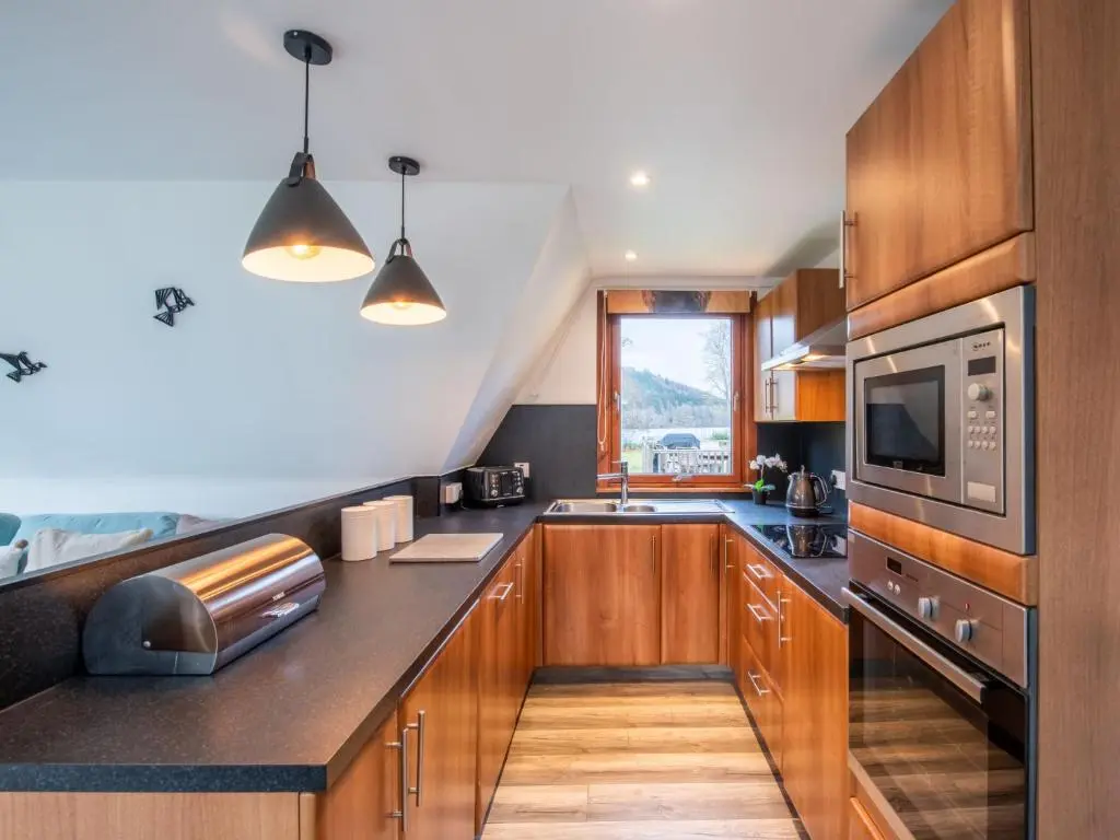 a kitchen with wooden cabinets and stainless steel appliances at Chalet Lodge 6 by Interhome in Spean Bridge