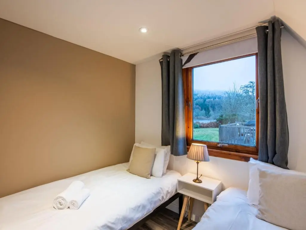 two beds in a room with a window at Chalet Lodge 6 by Interhome in Spean Bridge