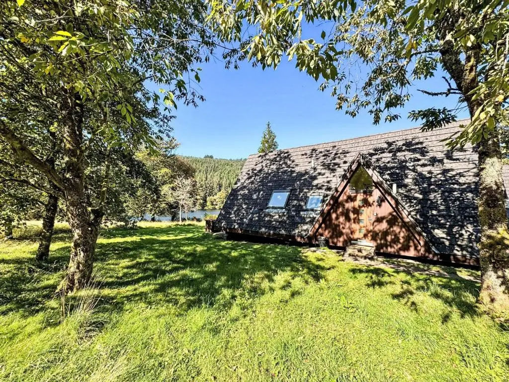 a barn in the middle of a field with trees at Chalet Lodge 6 by Interhome in Spean Bridge