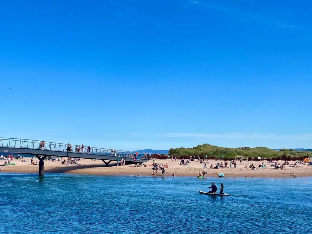 a group of people on a beach and a bridge at The Annexe in Lossiemouth